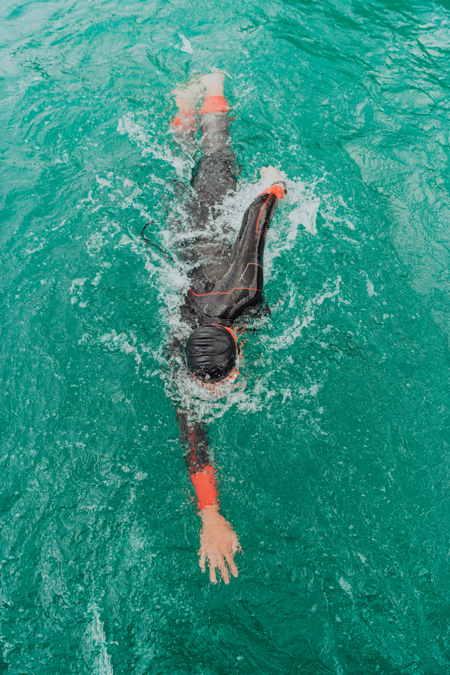 A triathlete in a professional swimming suit trains on the river.